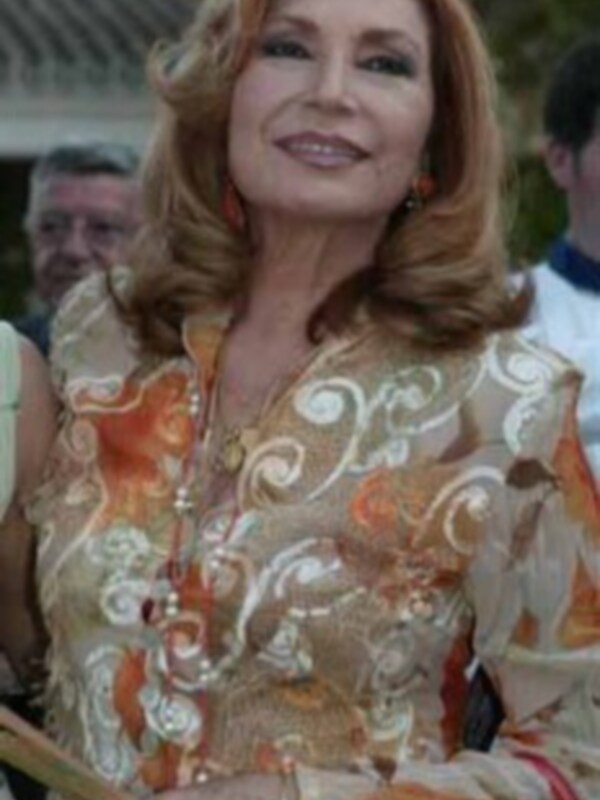 Una mujer con vestido dorado y naranja, sosteniendo un objeto rojo en la mano izquierda.