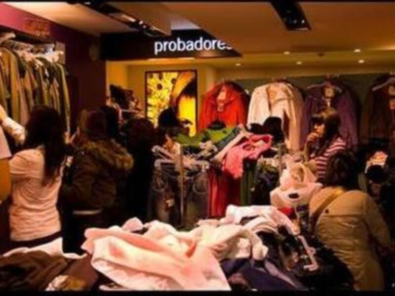 Tienda de ropa con colgadores y prendas variadas.