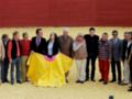 Grupo de personas posando con una capa de torero en un ruedo de toros.