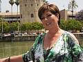 Una mujer con un vestido verde y negro posa frente a la Torre del Oro en Sevilla, España.