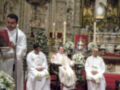 Celebración religiosa en un altar ornado con figuras y flores, con sacerdotes en trajes blancos y rojos.