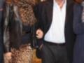 Imagen de una persona con un traje negro y chaqueta, junto a otra con vestido estampado de leopardo. Ambos están en un evento formal, posiblemente una gala o fiesta.