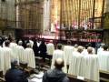 Una ceremonia religiosa en un templo, con personas vestidas con capas blancas y un altar al fondo.