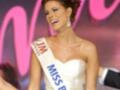 Miss Barcelona competes in a beauty pageant, wearing a white gown and sash.