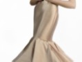Elegante vestido de noche en tono beige con detalles rojos y volantes en la falda, diseñado con un escote en V profundo y mangas sin mangas. La pieza combina elegancia y sofisticación, perfecta para eventos formales.