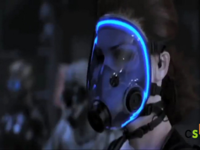 Person wearing a futuristic helmet with glowing blue lights, set against a dark, industrial background.