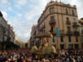 Procesión religiosa con una imagen de la Virgen en un carro, rodeada por una multitud en una plaza histórica.