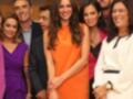Una foto de grupo con varias personas, incluyendo a una mujer en un vestido naranja que parece ser la protagonista. El ambiente es formal, posiblemente en una presentación o evento profesional.