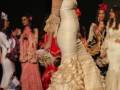 Desfile de moda flamenca con vestidos tradicionales y elegantes en un pasarela.