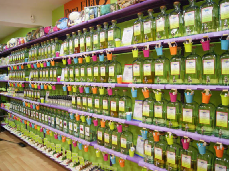 Una estantería llena de botellas de licor verde con etiquetas amarillas y colgantes en diferentes colores. La estantería está organizada en filas, mostrando una variedad de productos.