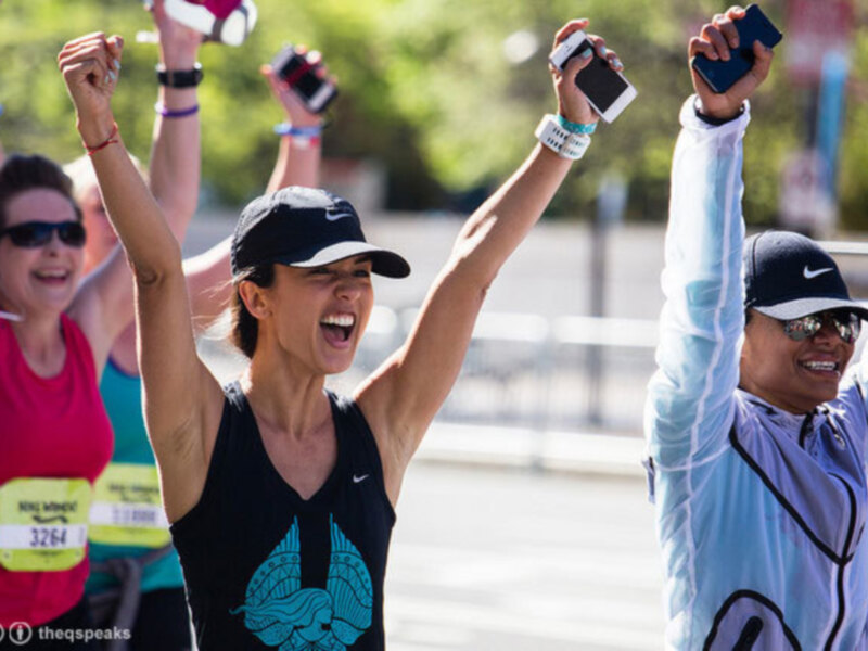 Corredores de maratón celebrando con las manos en alto, sonriendo y mostrando su energía.