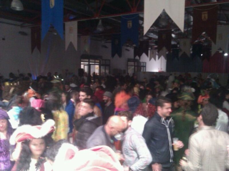 Una multitud de personas en un evento festivo, con banderas y decoraciones en el techo.