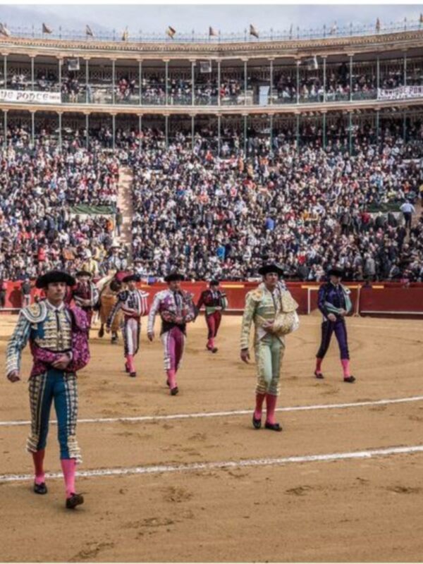 Toreros en el centro de la plaza de toros, con el público llenando los palcos al fondo.
