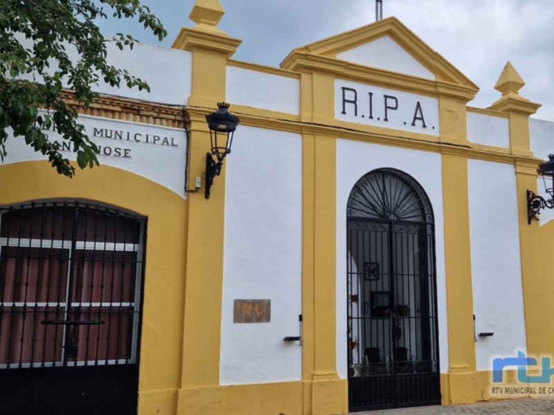 Fachada de la R.I.P.A. Municipal, edificio blanco y amarillo con detalles en negro, puertas metálicas y un techo triangular.