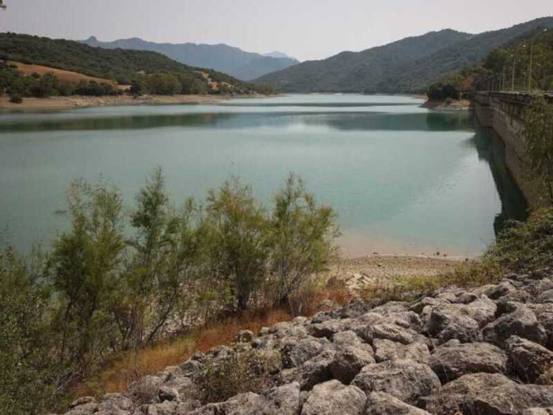 Lago con agua turquesa, rodeado de montañas y vegetación.