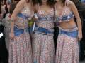 Tres jóvenes vestidas con trajes de baile en un ambiente festivo.