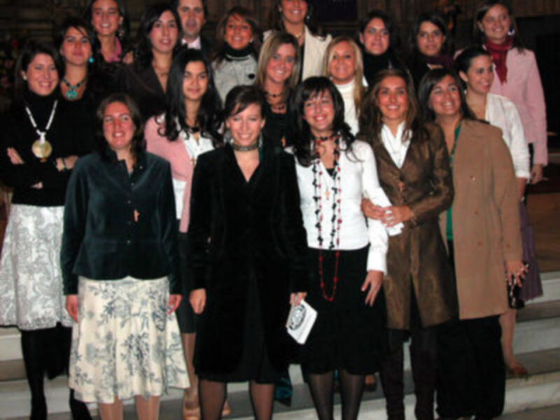 Gruppo di donne in piedi su una scalinata, vestite con abiti eleganti e colorati.