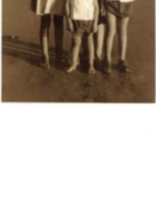 Una familia con tres niños, dos niñas y un niño, posando en una playa. La imagen es en blanco y negro, sugiriendo que podría ser de hace tiempo atrás.