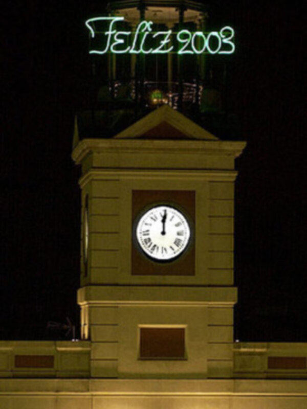 Torre con reloj y texto "Feliz 2003" en la noche.