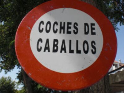 Señal de tráfico roja y blanca que dice 'COCHES DE CABALLOS' en español, advirtiendo sobre el paso de vehículos a caballo.