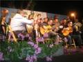 Orquesta de guitarra en un escenario con flores en primer plano