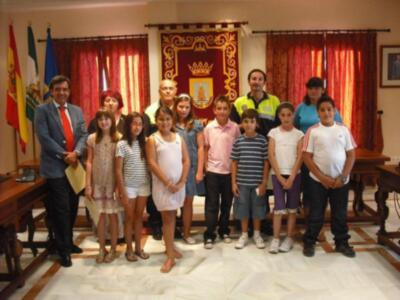 Una familia y niños posan en una sala con banderas y un escudo, probablemente en un evento oficial.