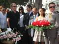 Una familia en un funeral, con flores rojas y blancas en el centro.