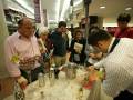 Un evento de degustación de vinos en un centro comercial, con personas degustando diferentes tipos de uvas y charlando con los vendedores.