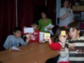 Niños participando en una actividad creativa, mostrando sus trabajos y escuchando a una adulta en un ambiente educativo.