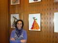 Una mujer sonríe en un entorno con arte enmarcado en la pared.