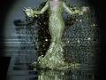 Vicky Martín Berrocal en una pasarela de alta costura, con un vestido dorado brillante y escotado que resalta en la oscuridad.