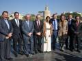 Grupo de personas en trajes formales posando frente al Torre del Oro en Sevilla.