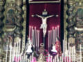 Cristo crucificado en un altar con velas encendidas y figuras religiosas alrededor.