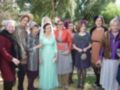 Grupo de mujeres elegantes posando juntas en un evento al aire libre, rodeadas de árboles y sosteniendo copas de vino.