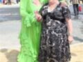 Dos mujeres sonrientes posan juntas en un evento público, una con un vestido verde y la otra con un vestido negro.