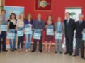Presentación del evento 'Autismo Sevilla' con participantes sosteniendo carteles promocionales.