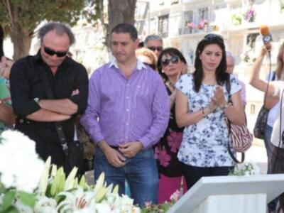 Una familia en un funeral, con flores y velas.
