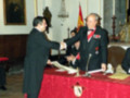 Entrega de una condecoración en una ceremonia formal en un entorno religioso.