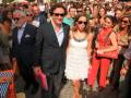 Un grupo de personas caminando por una alfombra roja, algunos con sombrillas y otros con accesorios de moda.