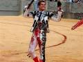 Un torero celebra con un trofeo en una plaza de toros, rodeado por espectadores.
