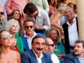 Una multitud de personas en un evento, algunos con gafas de sol y otros con camisas formales. La imagen muestra una diversidad de estilos y edades, con un ambiente social y relajado.