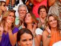 Grupo de personas en un evento, algunas sonríen y aplauden mientras otros observan.
