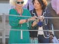 Dos mujeres intercambiando pulseras en un entorno al aire libre, rodeadas por otros espectadores.