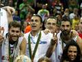 Equipo español de baloncesto celebrando una victoria con medallas y banderines en el escenario.