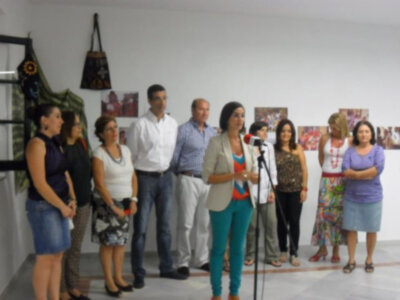 Una persona se encuentra en el centro, con un micrófono, frente a una fila de personas. La escena se desarrolla en un ambiente interior con decoración y carteles en el fondo.