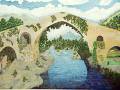 Puente medieval sobre un río con paisaje montañoso y vegetación.