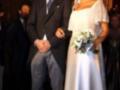 Una pareja casada en una boda, el hombre con traje y corbata azul, la mujer con vestido blanco y velo.