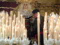 Imaginación: Un altar adornado con velas y flores blancas, con un hombre en el fondo, posiblemente en un acto religioso o ceremonial.