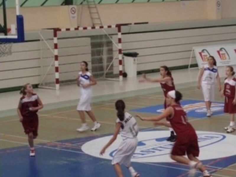 Partido de baloncesto femenino en un gimnasio, jugando contra un marcador.