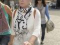 Mujer caminando con bufanda blanca y negra en una calle urbana.